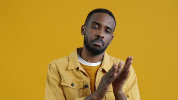 失望した若いアフリカ系アメリカ人男性の肖像画義務から手を切断し 黄色の色の背景に退屈立ってカメラを見て — ストック動画