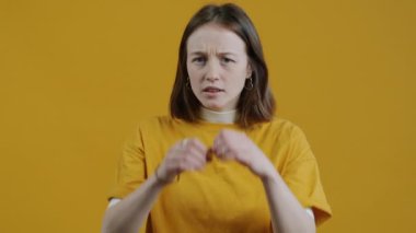 Sarı arka planda duran hayali dürbünle kameraya bakan komik kızın yavaş çekim portresi. İnsanlar ve ifadeler kavramı.