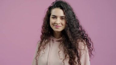 Kendine güvenen genç bir kadının portresi kendini gösteriyor ve pembe arka planda gülümsüyor. Milenyum ve deyimler kavramı.