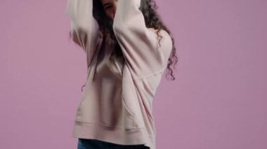 Heyecanlı bir kızın el hareketi yapması sonra da pembe renkli arka planda zaferi kutlamak için dans etmesi. İnsanlar ve duygular.