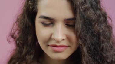 Burnu kırışık, kafası sallanan, pembe arka planda neşeli gülümseyen komik genç bir kadının yakın plan portresi. İfadeler ve duygular.