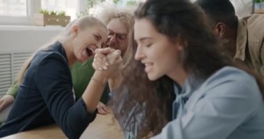 İş kadınları ofiste bilek güreşinde yarışıyorlar. Moladan zevk alıyorlar. Birlikte gülüyorlar..
