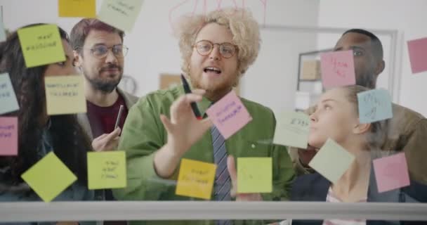 Çeşitli Adamları Yapışkan Notlar Cam Pano Kullanarak Ofiste Beyin Fırtınası — Stok video