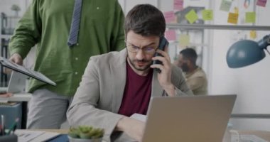 Ofis çalışanı cep telefonundan arıyor ve rahatsız ve yorgun hisseden meslektaşından daha fazla evrak alıyor. İnsanlar ve iş yükü kavramı.