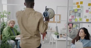 İnsanlar dinlerken ve kulaklarını kapatırken modern ofisteki mutsuz çalışanlarla konuşan hoparlörlü patron. İş ve liderlik kavramı.