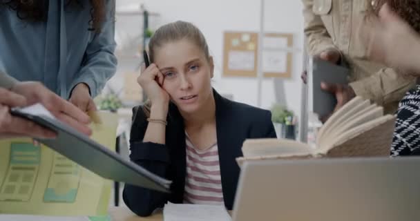 当一群人在办公室里要求工作和关注时 一个疲惫不堪的年轻女商人坐在办公桌前的画像 人与职业概念 — 图库视频影像
