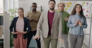 Komik genç iş adamları tatilde ofiste spor yapıyor sağlık eğitimi alıyor ve takım oluşturmaktan keyif alıyorlar..