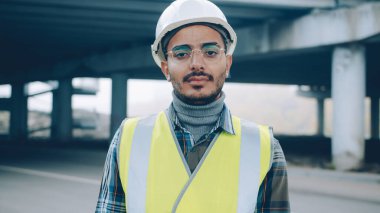 Üniformalı genç bir Arap 'ın portresi endüstriyel bölgede tek başına dikiliyor ve kameraya bakıyor. İstihdam ve profesyoneller konsepti.