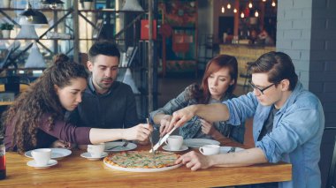 Mutlu genç insanlar yakın arkadaş büyük pizza-are kupür bıçak ile konuşmak ve samimi kafede yemek sırasında gülüyor. Modern yaşam tarzı, Gastronomi ve dostluk kavramı.
