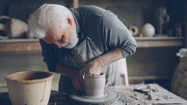 Zkušený Keramik Šedovlasý Vousatý Muž Vyhlazuje Tvarovaný Keramický Hrnec Vlhkou — Stock fotografie