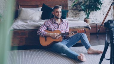 Yakışıklı bir adam blogger ve gitarist gitar hakkında video dersini yatak odasında kamera ile kayıt. Sakallı adam onun takipçileri tebrik, söz ve gitar parçaları gösterilen.