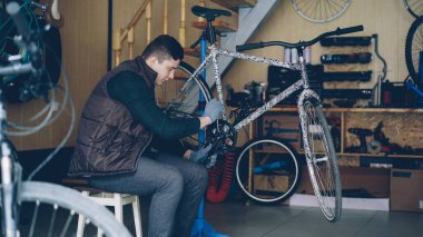 Deneyimli usta ile çok sayıda yedek parçalar ve donatım atölyesinde çalışırken özel araçları anahtar anahtar ile Bisiklet pedalla onarıyor. İnsanlar ve bakım kavramı.