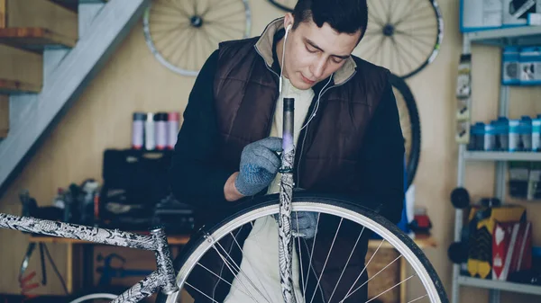 집중된 기계공 자전거 바퀴를 기름을 바르기 스튜디오에서 자전거를 이어폰 자신의 — 스톡 사진