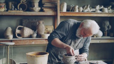 Deneyimli usta sakallı adam kulak seramik kase için yapım ve rahat işyerinde çalışırken clayware üzerinde sabitleme. Çanak çömlek, meslek ve hobi kavramı.