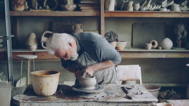 Yetenekli yaşlı erkek potter dönüm tekerlek işyerinde güzel seramik potu üretiyor. Oluşturma işlemi, geleneksel seramik ve ilginç hobi kavramı.