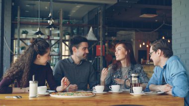 Mutlu ve çekici grup kadın ve erkek arkadaşıyla Sohbet ve birlikte bir küçük modern kafe veya pizza evde gülüyor. İletişim ve gıda hizmet kavramı.