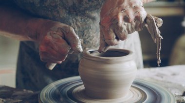 Yaşlı sakallı usta seramik kavanoz profesyonel araçlar kullanarak potters tekerlek üzerinde yaratıyor. Çalışma alanı ile el yapımı tencere, güzel vazolar ve arka plan resimler.