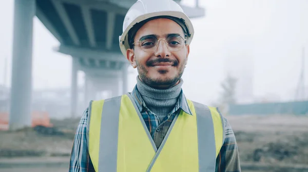 Porträtt Glad Arabisk Man Bär Skyddshjälm Och Väst Leende Stående — Stockfoto