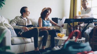 Müzikal grup performans şarkı ve müzik aletleri müzik sayfasına bakarak ev stüdyosu oynamaya prova yapıyor. Bira şişeleri ve tablo snacks görülebilir.