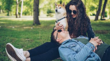 Çekici gülümseyen kadın onunla konuşmayı ve güzel iyi yetişmiş köpek okşama neşeli genç adam parkta çim kafasıyla hanımları bacaklarına yalan söylüyor.