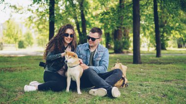 Seven çift heyecanlı gençler onun kürk tırmalamak, söz ve çim parkta oturan gülüyor sevimli köpek shiba Inu Füssing. İnsanlar ve evcil hayvanların kavramı.