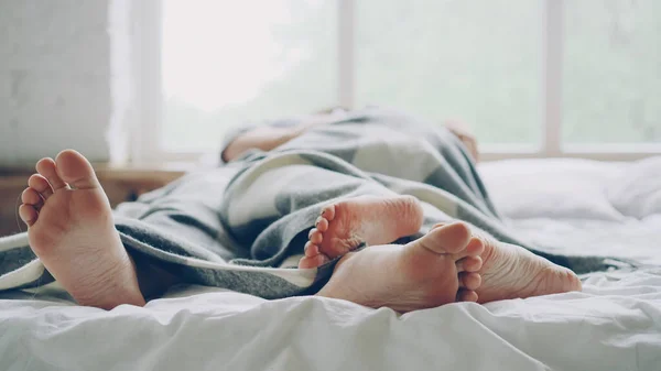 夫と妻が毛布の下のベッドで横たわっているとお互いに触れて裸の足に焦点を当てる ハグの話 ロマンチックな関係 肉体と愛情のある人々 の概念 — ストック写真