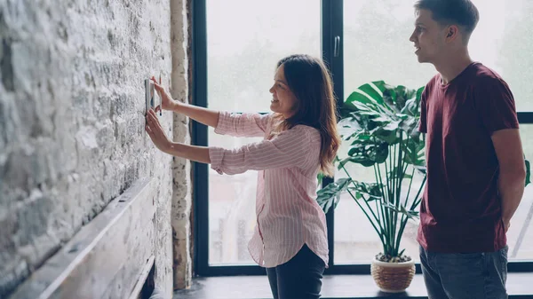 Joyeux Jeune Femme Choisit Endroit Pour Photographie Encadrée Sur Mur — Photo