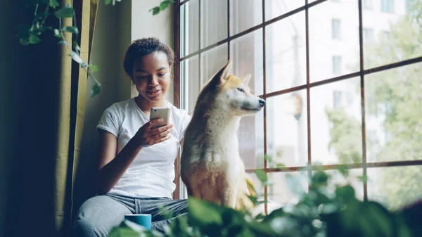 Mooie Jonge Vrouw Zit Vensterbank Gebruikend Smartphone Terwijl Haar Schattige — Stockfoto