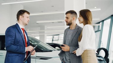 Onlara lüks otomatik modeli hakkında anlatıyor süre baktılar genç çift erkek ve kadın araba bayilik Manager'da konuşuyorsun. Güzel insanlar, ulaşım ve iş kavramı.