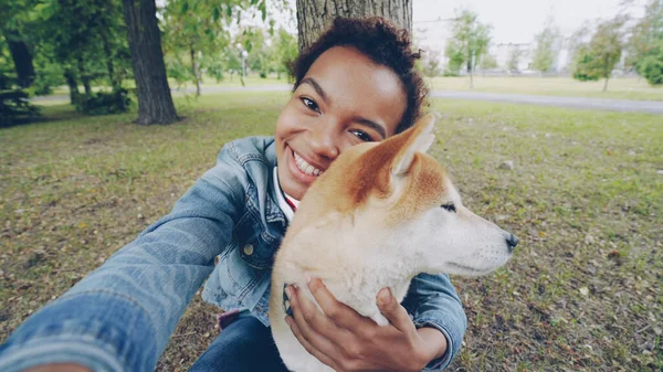 視点カメラを保持している都市公園のかわいい子犬と Selfie を取っているのはかなりアフリカ系アメリカ人の女の子笑顔とポーズのショット 近代的な技術 自然と動物の概念 — ストック写真