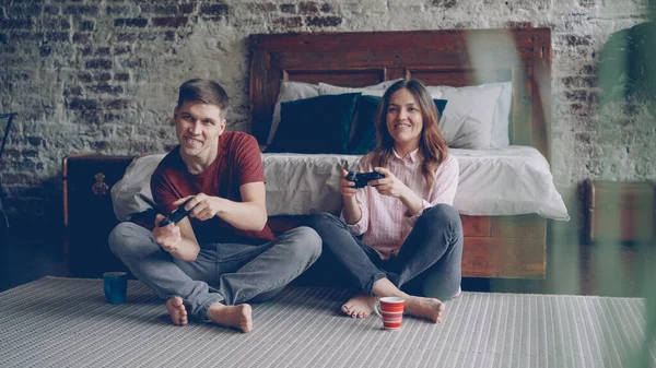 可爱的年轻夫妇的男友和女友正在玩游戏 手持操纵杆坐在卧室地板上的家 情感爱好者正在享受电脑游戏 — 图库照片