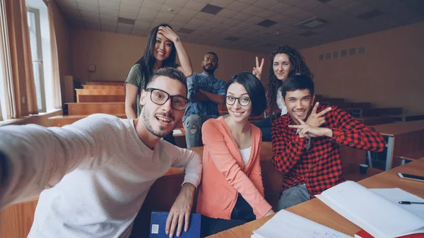 友人学生 カメラ目線の教室で Selfie を取って手のジェスチャーでポーズと笑顔の多民族のグループのビュー ポイントのショット 近代的な技術と新世紀の概念 — ストック写真