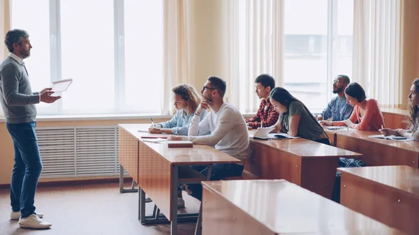 Grupa Studentów Siedząc Przy Stolikach Klasie Dokonywanie Notatek Rozmawia Mężczyzna — Zdjęcie stockowe