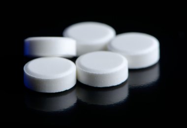 Parlak siyah arka plan üzerine beyaz hap (tablet)