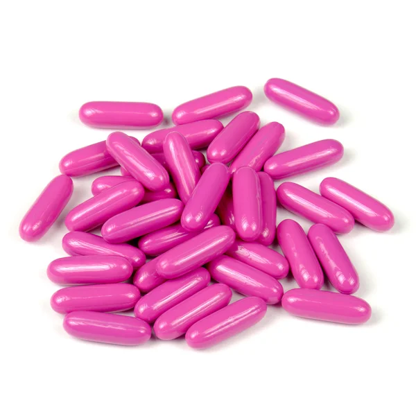 Розовые таблетки (капсулы) на белом фоне — стоковое фото