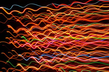 koyu arka plan üzerinde dalgalı renkli parlak çizgiler