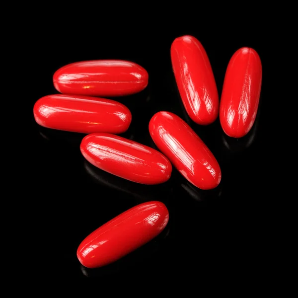 Pastillas rojas (cápsulas) sobre fondo negro — Foto de Stock