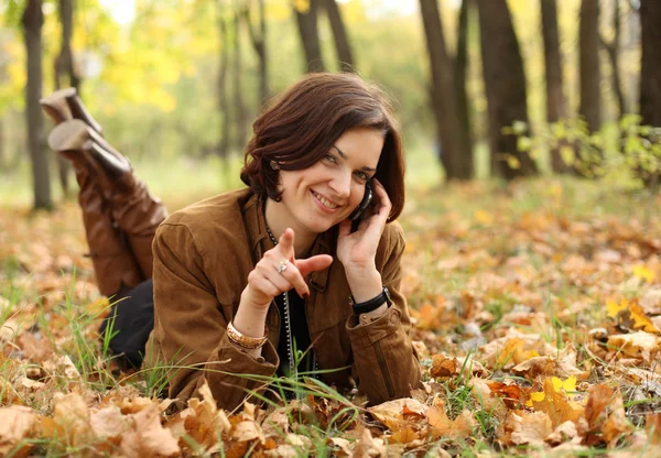 Женщина звонит по телефону в осенний парк — стоковое фото