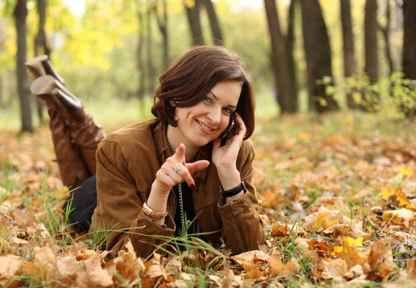 Žena volá po telefonu v podzimním parku — Stock fotografie