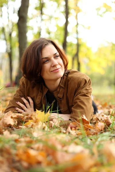 Frau liegt auf Laubteppich im Herbstpark — Stockfoto