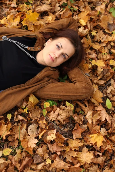 Donna sdraiata su un tappeto di foglie nel parco autunnale — Foto Stock