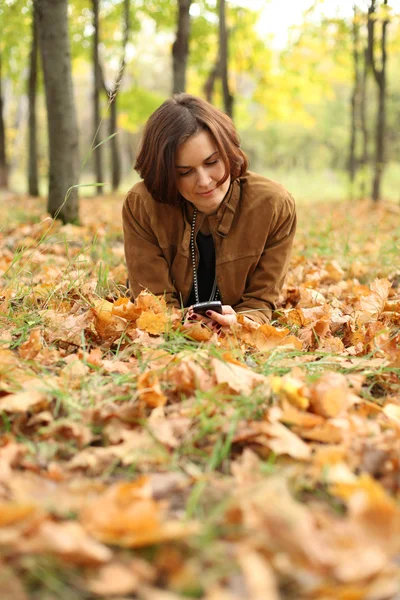 Žena ležela na koberci listí v podzimním parku — Stock fotografie