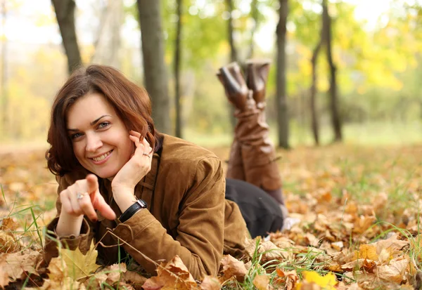 Mujer acostada en una alfombra de hojas en el parque de otoño — Foto de Stock