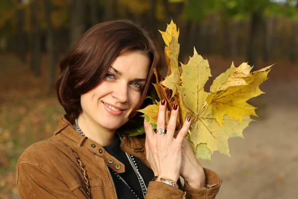 Schöne Frau mit einem Strauß Ahornblättern — Stockfoto