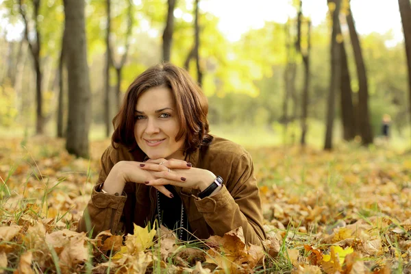 Frau liegt auf Laubteppich im Herbstpark — Stockfoto