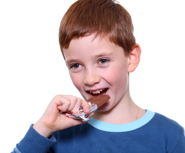 Malý chlapec jíst čokoládu izolovaných na bílém — Stock fotografie