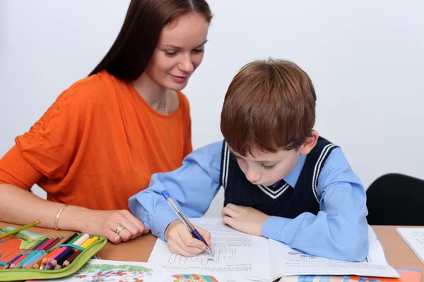 Mother or teacher helping kid with schoolwork — Stock Photo, Image