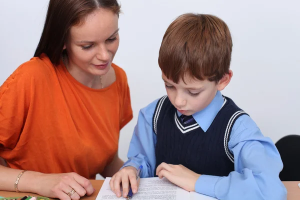 Mother or teacher helping kid with schoolwork — Stock Photo, Image