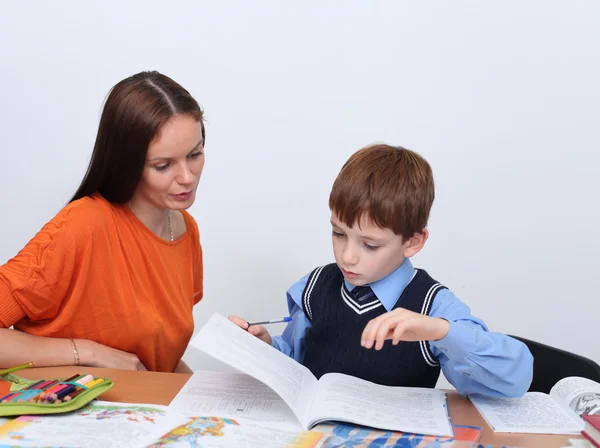 Мать или учитель помогает ребенку с школьной работой — стоковое фото