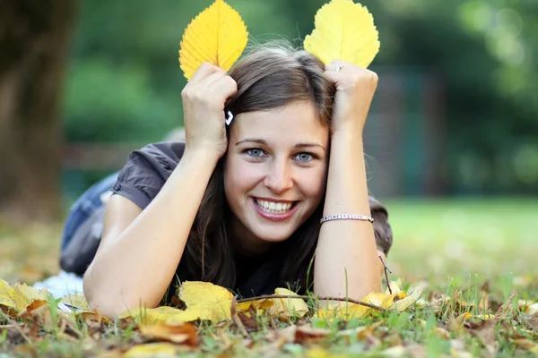 Femme couchée sur un tapis de feuilles dans le parc d'automne — Photo